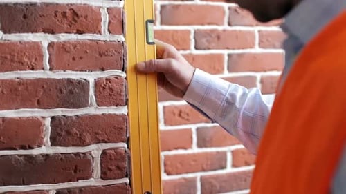 A construction engineer checks the walls with a level.
