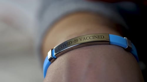 Femme participant au programme de vaccination contre le coronavirus avec bracelet ou étiquette vacciné à portée de main