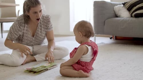 Mom Reads Picture Book to Baby Indoors