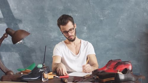 Man Drafting Shoe Design at Desk
