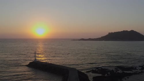 Eine romantische Landschaft, in der die untergehende Sonne den Leuchtturm und die Insel erleuchtet