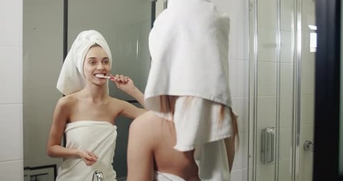 Woman Brushing Teeth in Bathroom Mirror