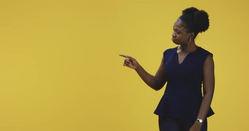 Woman Pointing and Smiling on Yellow Background