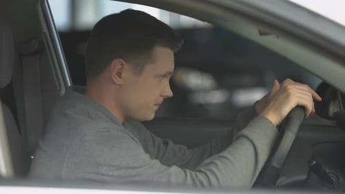 Distraught Man Sitting in Car with Head Down