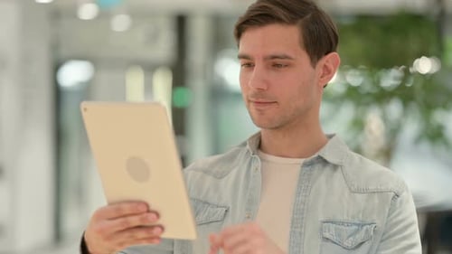 Young Adult Using Tablet in Modern Workplace