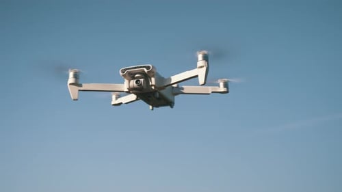 White Drone Flying on Nature Background. Drone Hanging in Air Flying Helicopter Dron Remote Control