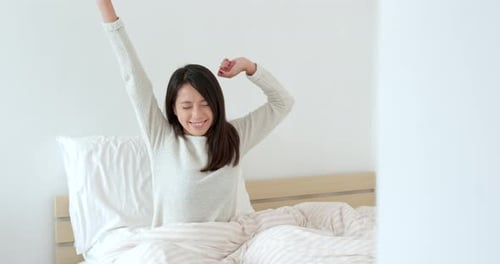 Woman Wakes Up and Stretches in Bed