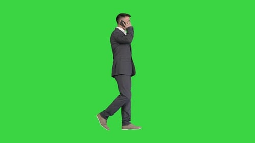 Businessman Walking and Talking on Mobile Phone on a Green Screen, Chroma Key.