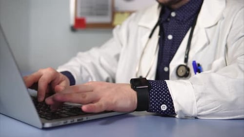 Close Up Shot of an Adult Doctor's Hand, Who Prints Text on the Laptop Keyboard