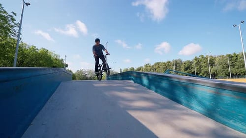 Cyclist Jumps on Bike Ramp in Skate Park