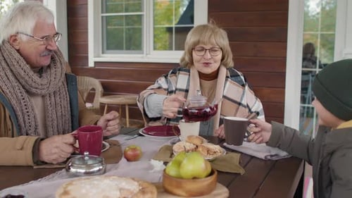 Kid and Grandparents Drinking Tea on Outdoor Terrace