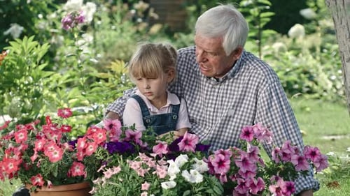 Grandfather and Child Enjoying Flowers in a Garden