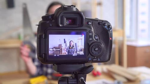 Una joven y hermosa bloguera de bricolaje escribe un Vídeo en un taller de garaje usando