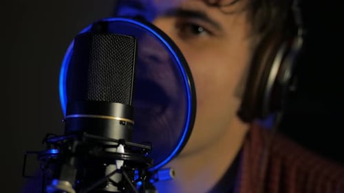 Young Man Headphones Sings Song Near Microphone Recording Studio Under Natural Light