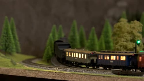 A Model Train Running Along Tracks Outdoors in Forest.