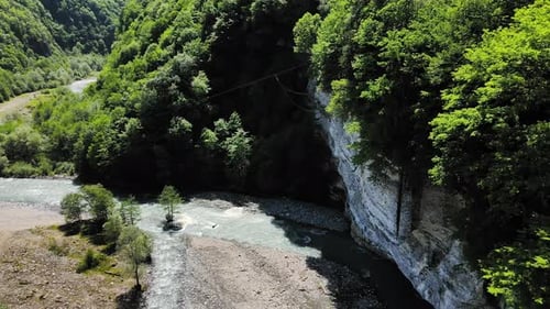 Flying Over the Valley of a Blue Mountain River with High Cliffs