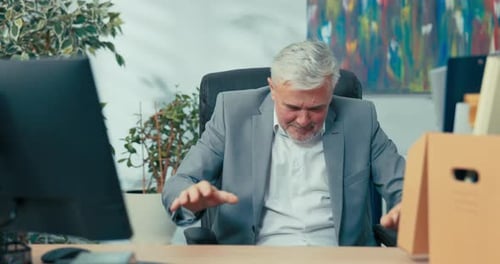 Happy Businessman Cheering at Desk in Office