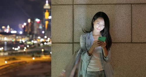 Woman Uses Phone with Blurry City View at Night