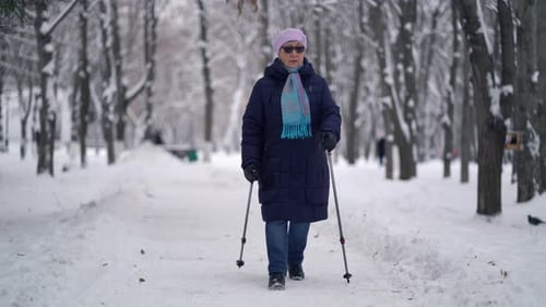 Senior Woman Nordic Walking in Snowy Park