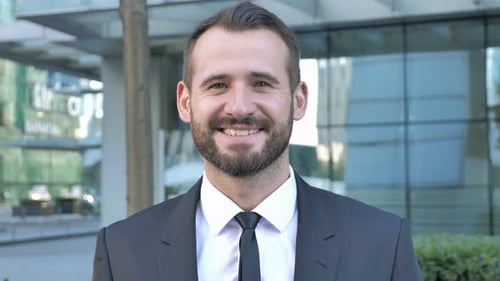 Happy Businessman Smiling in Front of Glass Building