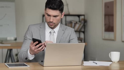Adult Man Working with Phone and Laptop