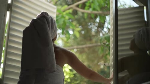 Woman in Towel Opens Window in Tropical Home