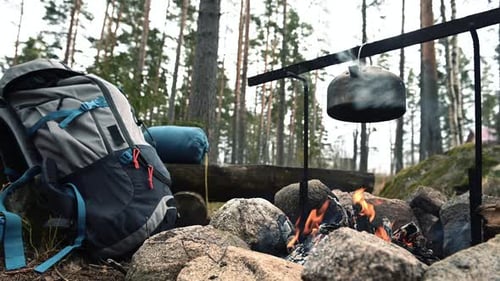 Backpack and Metal kettle on a campfire in the forest