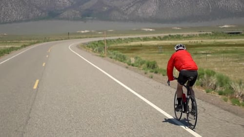 A man road biking on a scenic road.