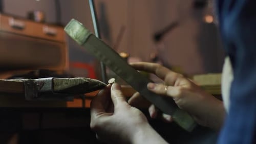 Nahaufnahme der Hände einer kaukasischen Juwelierin, die in der Werkstatt Schmuck herstellt