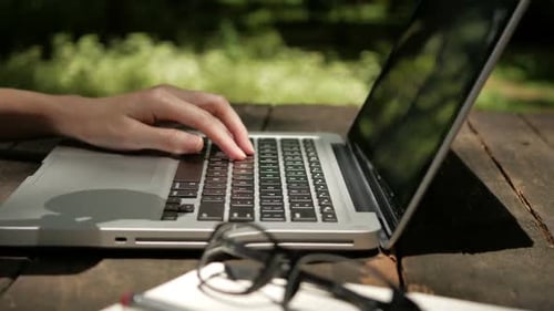 Frau tippt auf Laptop und trinkt Kaffee