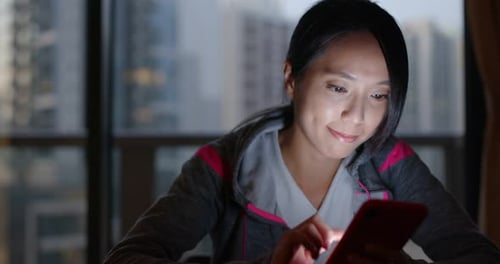 Woman Using Smartphone at Night in City Apartment