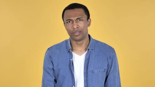 Young Adult Male Expressing Disagreement on Yellow Backdrop