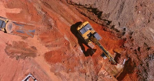 Heavy Machinery Excavating Red Earth from Above