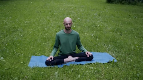 Man Does Yoga on the Lawn in His Own Garden Breathing Exercise in Lotus Position