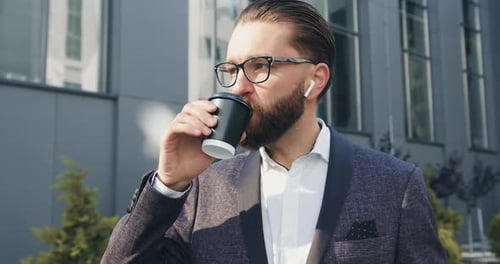Man in Glasses Which Drinking Coffee Near Modern Urban Building while Going to His job