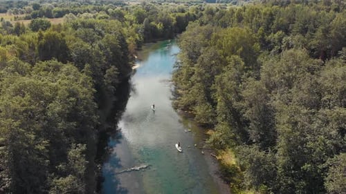 People Sailing on Boats Down the River Between the Forest