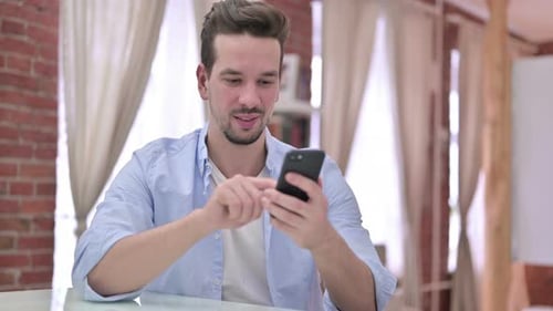 Smiling Adult Using a Smartphone Indoors