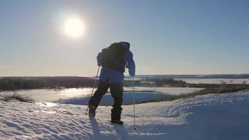 Hiker Climbing Snowy Hill on Bright Winter Day