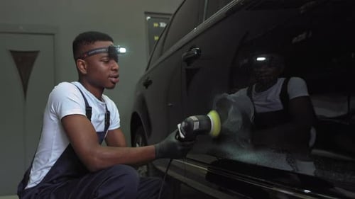 Young Adult Polishing Black Car in Garage