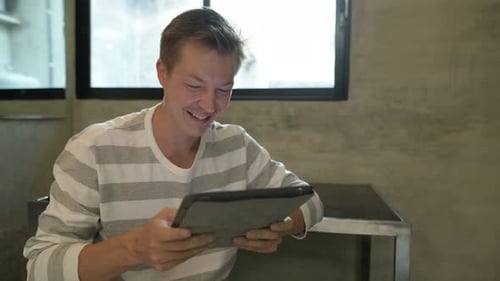 Smiling Man Using Tablet Indoors