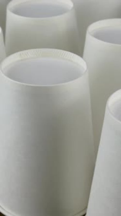 Row of White Disposable Paper Cup for Coffee or Hot Beverage on Dark Backdrop Rotate Slowly