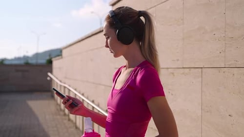 Woman in Active Wear Checks Phone, Drinks Water