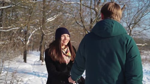 Glückliches Paar spaziert im Winterwald, spielt und wirft Schnee