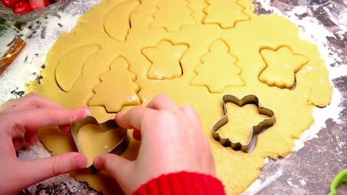 Child Using Cookie Cutters on Christmas Cookie Dough