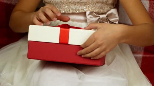 Child Opens Gift with Red Ribbon Inside Home