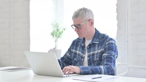 Fleißiger, lässiger Mann mittleren Alters trinkt Kaffee und arbeitet