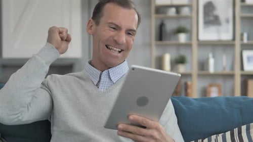 Man Cheering with Tablet at Home