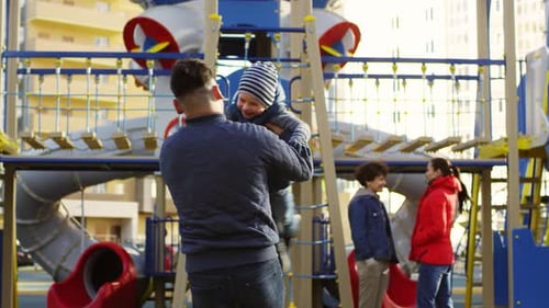 Liebevoller kaukasischer Vater dreht sich mit Sohn auf dem Spielplatz herum