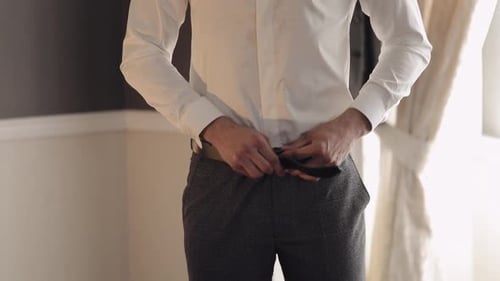 Groom Wears Belt Man in White Shirt Puts Belt on Pants in Wedding Morning Businessman Preparation