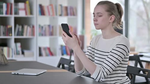 Smartphone Use By Serious Young Woman in Library
